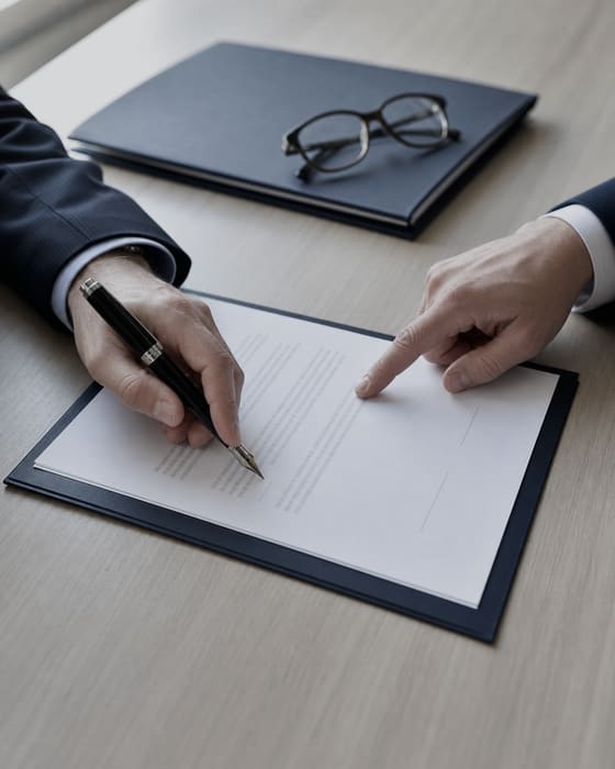 Signature d'une convention de stage : une main signe au stylo plume pendant qu'une autre désigne un paragraphe du document