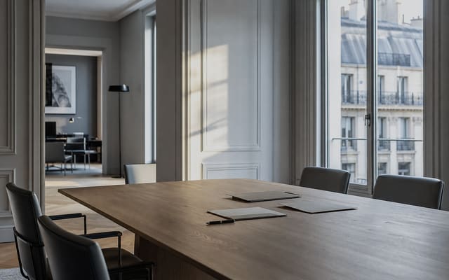 Salle de réunion d'un cabinet d'expertise comptable parisien, table en chêne clair devant une fenêtre haussmannienne